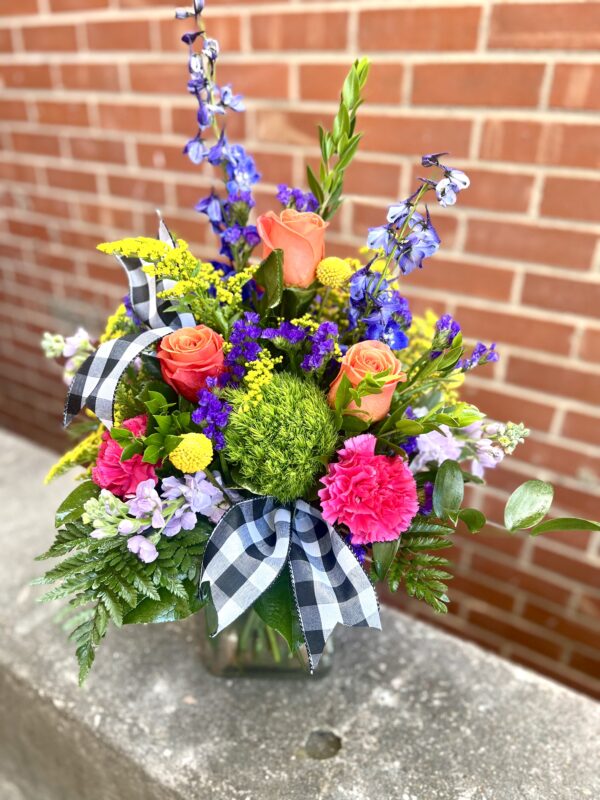 Uncover the beauty of “Garden Secrets” from Flowerland Florist in Sulphur Springs, TX. Bursting with roses, carnations, delphinium, and vibrant greenery in bold hues of pink, purple, yellow, and green—this lush arrangement is perfect for any joyful occasion. Local delivery available.