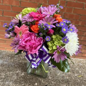 Brighten someone’s day with “Blooming Joy” from Flowerland Florist in Sulphur Springs, TX. Bursting with vibrant daisies, hydrangeas, carnations, and more in cheerful shades of pink, orange, purple, and green. A joyful floral arrangement for any occasion. Local delivery available.