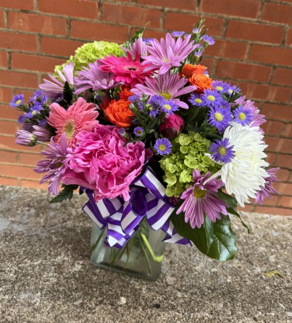 Brighten someone’s day with “Blooming Joy” from Flowerland Florist in Sulphur Springs, TX. Bursting with vibrant daisies, hydrangeas, carnations, and more in cheerful shades of pink, orange, purple, and green. A joyful floral arrangement for any occasion. Local delivery available.