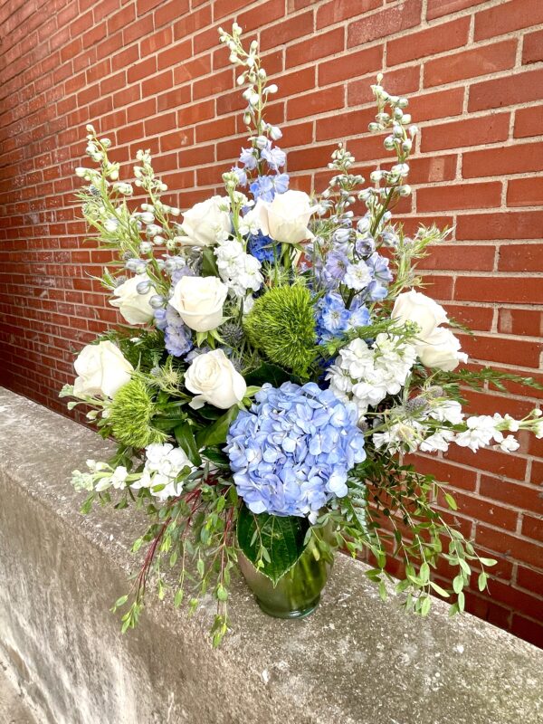 Make a serene statement with “Ocean Whisper” from Flowerland Florist in Sulphur Springs, TX. This elegant arrangement features blue hydrangeas, white roses, and cascading greenery—perfect for sympathy, memorials, or peaceful home décor. Local delivery available.